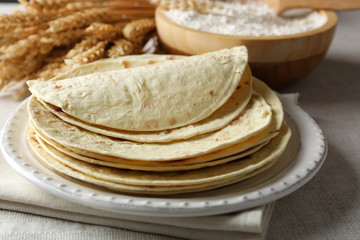 Stack of homemade whole wheat flour tortilla on napkin, on light background