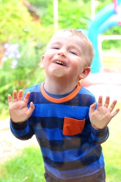 Portrait Of A Child Pulling Faces Behind The Window