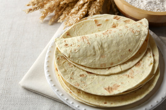 Stack of homemade whole wheat flour tortilla on napkin, on light background