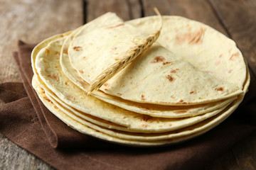 Stack of homemade whole wheat flour tortilla on napkin, on wooden background