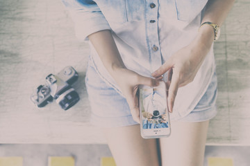 Woman view image on smartphone screen and vintage camera.