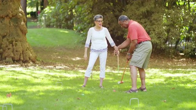 Mature Black Friends Playing Croquet Outside in a Park