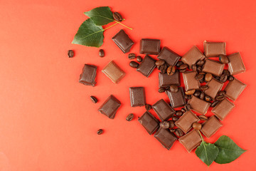 Chocolate pieces with green leaves on red background