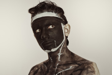 Studio portrait of a young man with a black theatrical makeup