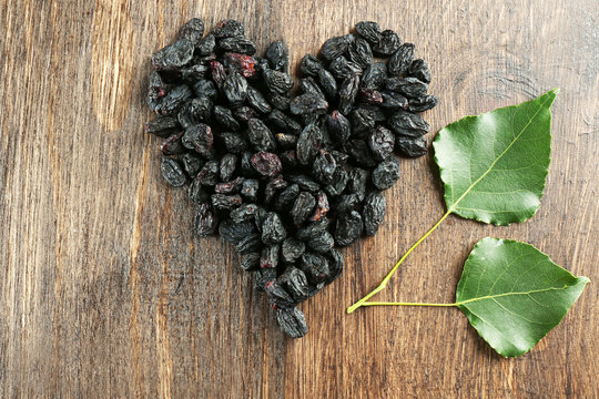 Raisins arranged in heart shape on wooden background