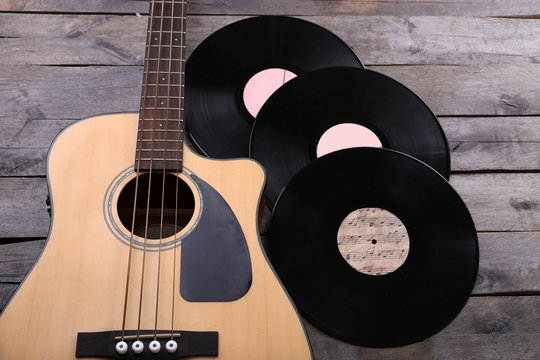 Guitar and vinyl records on wooden table close up
