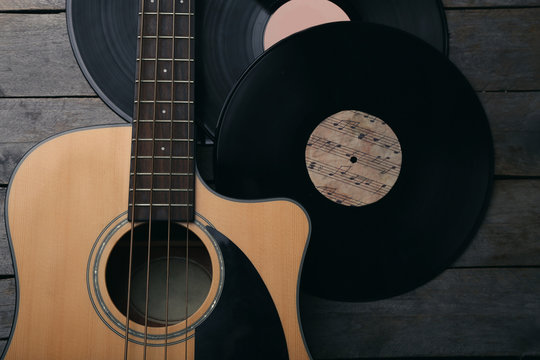 Guitar and vinyl records on wooden table close up