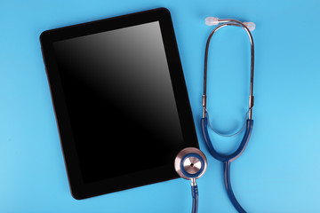 Fototapeta na wymiar Tablet and stethoscope on blue background