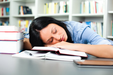 Tired student sleeping in library
