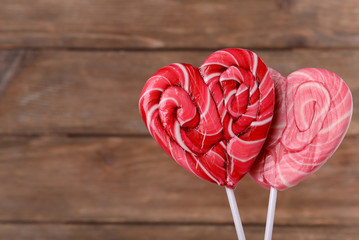 Bright lollipops in shape of heart on wooden background