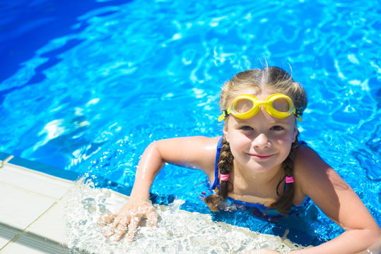 Smiling little girl in swimming goggles in the swimming pool