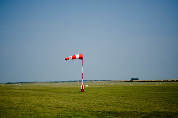 Airfield wind direction sign on the green grass with blue sky ba