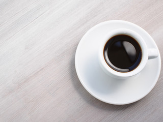 Cup of espresso coffee on white plate and wooden table
