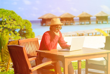 Young man with laptop at luxury beach resort