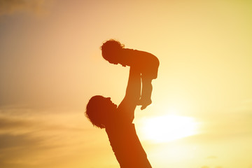 silhouettes of father and daughter playing at sunset