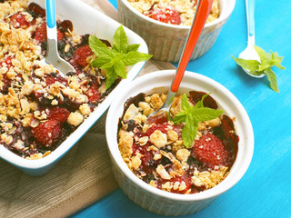 Portion of crumble with strawberries, red currants, blueberries and blackberries with crumb made of powdered sugar, almonds, flour and oatmeal flakes