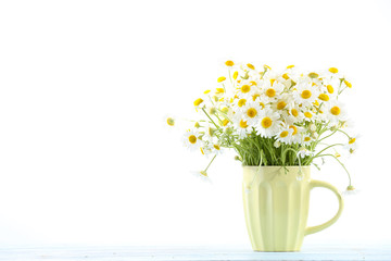 Beautiful bouquet of daisies in cup on light background