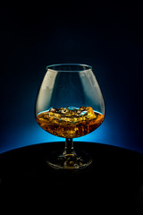 A glass of whiskey with ice on a black background