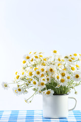 Beautiful bouquet of daisies in cup on light background