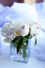 Beautiful white peonies in vase on fabric background