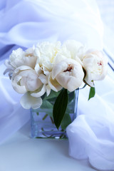 Beautiful white peonies in vase on fabric background