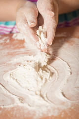 Little chef hands smeary with flour playing with dough