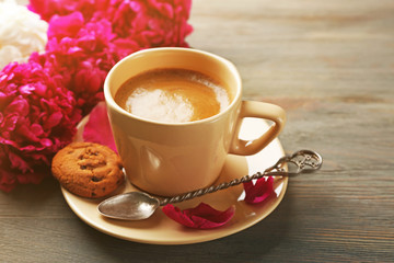 Composition with cup of coffee and peony flowers on wooden background