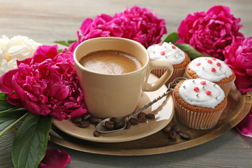 Composition with cup of coffee, muffins and peony flowers on wooden background
