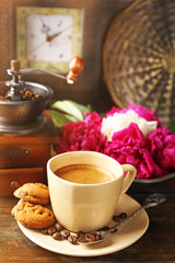 Composition with, coffee grinder, cup of coffee and peony flowers on wooden background