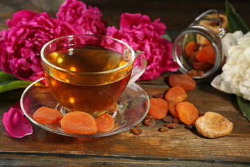 Composition with cup of herbal tea and peony flowers on wooden background