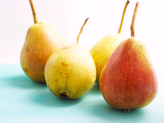 Pears in the sun light on green pastel wooden background
