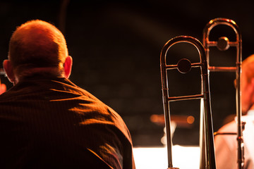 Big Band trombonist. A view of a big band trombone player sitting during a break in a rehearsal with his instrument on its stand nearby.