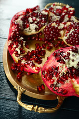Pomegranate seeds on metal tray on wooden table, closeup