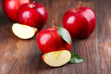 Red apples with leaves and slices on wooden table, closeup