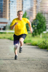 Sporty man jogging in city street park. Outdoor fitness.