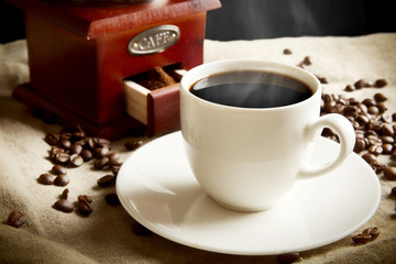 Long shot of cup of coffee,bag,coffee beans on flax linen
