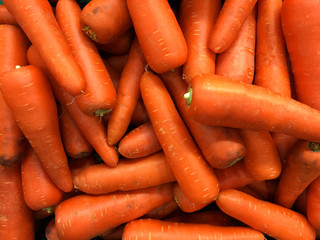 pile of department store carrot. Pile of well cleaned beheaded-off raw carrot ready for customer to pick in retail supermarket.