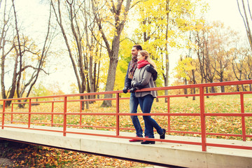 smiling couple hugging on bridge in autumn park