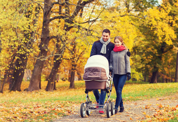 smiling couple with baby pram in autumn park