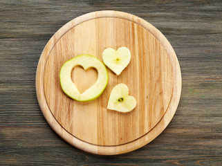 Apple slice with cut in shape of heart on wooden background