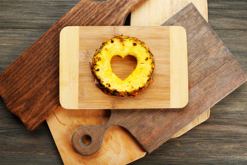 Pineapple slice with cut in shape of heart on wooden background