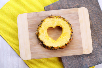 Pineapple slice with cut in shape of heart on wooden background