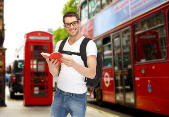 happy young man with backpack and book travelling