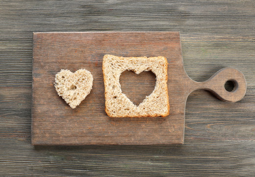 Bread slice with cut in shape of heart on wooden background