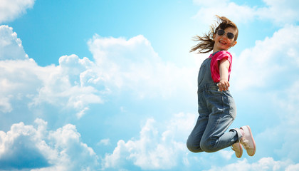 happy little girl jumping high over blue sky