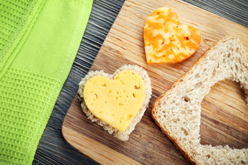 Bread slice with cut in shape of heart and cheese on table close up