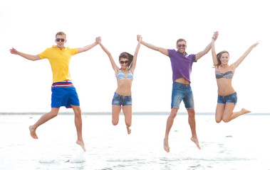 Fototapeta na wymiar group of happy friends jumping on beach