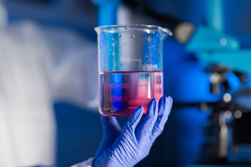 close up of hand holding glass in chemical lab