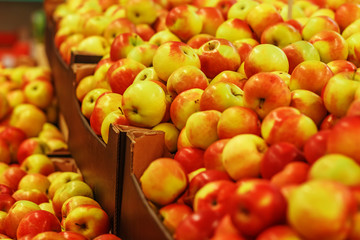 Many ripe yellow-red apples in boxes in the store
