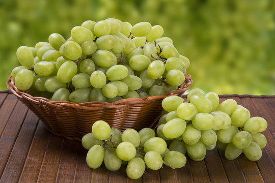 Green grapes in a basket over a wooden surface on a grape field